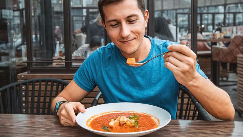 Man at table eating a bowl of soup