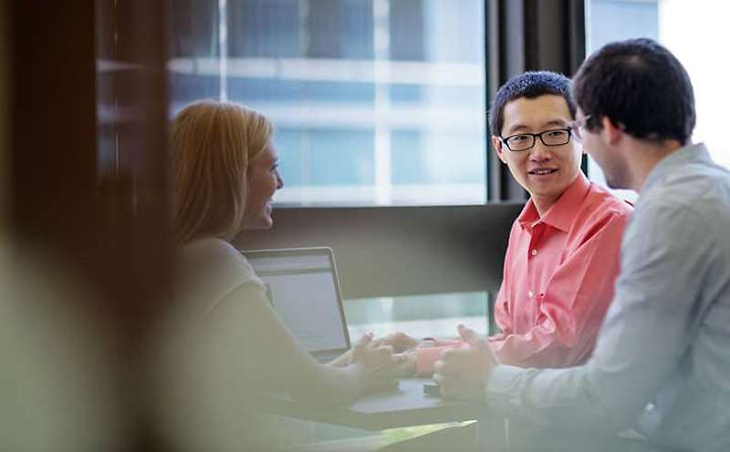 Three people having a discussion in a meeting room