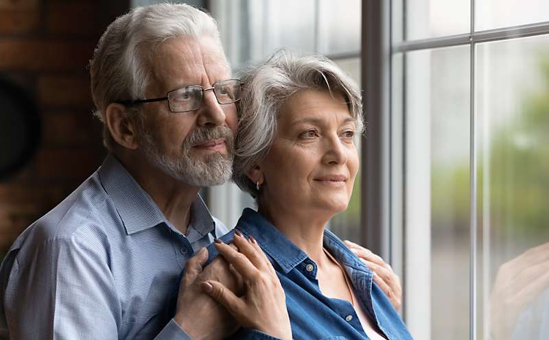 A couple holding one another and looking out the window
